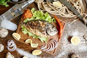 fraîchement pris poisson sur une en bois Coupe planche avec tranché citrons et Ail. photo