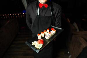 homme en portant plateau de Sushi dans Japonais restaurant photo