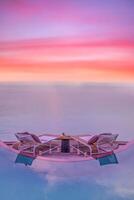 table d'amour et de romance d'été pour un dîner romantique avec des chaises de réflexion de piscine à débordement sous le ciel coucher de soleil et la mer en arrière-plan. dîner de destination de luxe, dîner romantique pour les couples photo