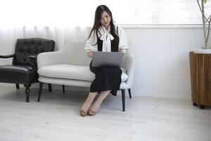 une Japonais femme vérification téléphone intelligent par éloigné travail dans le Accueil Bureau photo