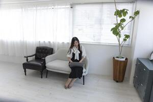 une Japonais femme vérification téléphone intelligent par éloigné travail dans le Accueil Bureau photo