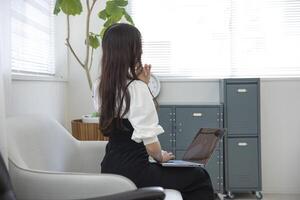 une travail Japonais femme par éloigné travail dans le Accueil Bureau fermer photo