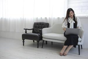 une Japonais femme vérification téléphone intelligent par éloigné travail dans le Accueil Bureau photo