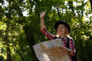 Jeune caucasien femme dans une chapeau avec une carte agitant dans salutation. flou arrière-plan, sélectif se concentrer. haute qualité photo