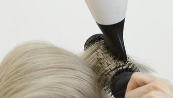 invisible coiffeur mains ligne le blond modèle cheveux en utilisant une cheveux séchoir et peigne. sélectif concentrer .haut qualité photo