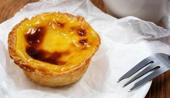 assiette avec un Portugais pastel de nata Quiche. pastel de belém est une monastique et culte Pâtisserie dans le forme de tasses avec une brûlé Haut et une croustillant bouffée Pâtisserie croûte. sucré dessert avec Oeuf crème. photo