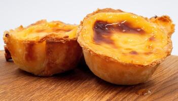 pastel de nata tartes ou Portugais Oeuf Tarte sur une en bois marron Contexte. pastel de belém est une petit tarte avec une croustillant bouffée Pâtisserie croûte et une Crème crème remplissage. sucré dessert. photo