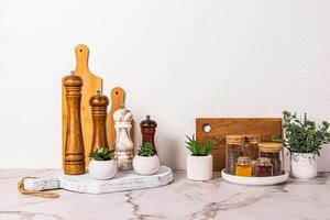 ensemble de divers pimenter moulins et verre pots avec assaisonnement sur blanc marbre comptoir. élégant cuisine Contexte dans lumière couleurs. minimalisme. photo