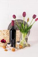 une magnifique de fête arrangement pour le juif Pâque vacances. une bouteille de rouge vin, matsot pain, une coup de kascher vin, noix. photo