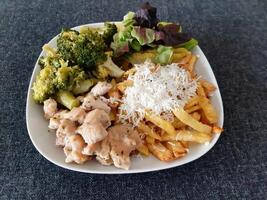 fait maison grillé poulet avec français frites, brocoli, fromage et vert salade, servi sur une blanc assiette photo