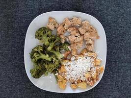 fait maison grillé poulet avec français frites, fromage et brocoli, servi sur une blanc assiette photo