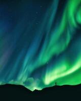 aurore borealis embrasé plus de promeneur permanent sur Montagne dans Arctique cercle photo