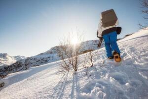 alpiniste homme escalade à le de pointe Montagne sur hiver à le coucher du soleil photo