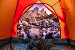 vue de à l'intérieur une tente de touristique relaxant et profiter le aiguilles d'Arves avec iconique Trois Montagne et cascade rapides écoulement dans français Alpes photo