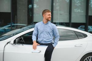 toujours disponible. Beau Jeune homme d'affaire près le sien voiture en plein air photo