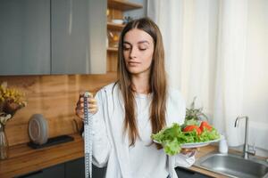 content Jeune femme en train de préparer salade dans cuisine. en bonne santé régime photo