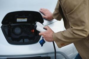 homme des charges un électrique voiture à le mise en charge station photo