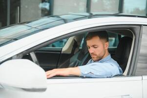 homme d'affaire en portant pilotage roue tandis que conduite moderne électrique voiture sur le rue route. sur de soi homme conduite coûteux auto. chauffeur tournant pilotage roue dans luxueux auto sur voyage photo