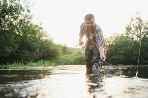 pêcheur captures une truite sur le rivière dans été photo