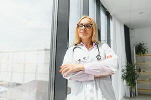 réussi mature caucasien Sénior femelle médecin dans blanc manteau à hôpital. photo