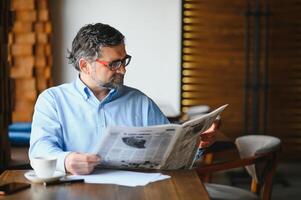 journal dans le Matin. Sénior homme d'affaire à le sien Bureau équitation journaux. photo