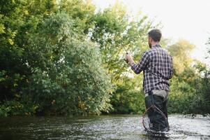 pêcheur captures une truite sur le rivière dans été photo