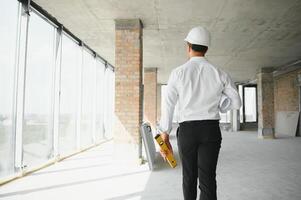 portrait de homme architecte à bâtiment placer. sur de soi construction directeur portant casque. réussi mature civil ingénieur à construction site avec copie espace. photo