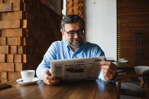 café Pause. homme en buvant café et en train de lire journal dans café bar photo