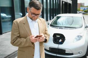 une homme d'affaire des charges un électrique voiture photo