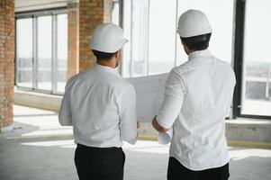 deux spécialistes inspecter commercial, industriel bâtiment construction placer. réel biens projet avec civil ingénieur photo