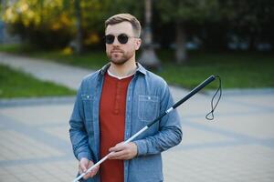 aveugle homme. gens avec invalidité, handicapé la personne et tous les jours vie. visuellement altéré homme avec en marchant bâton. photo