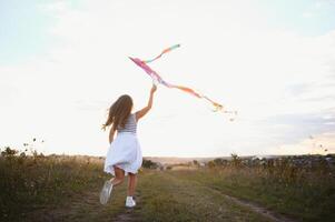 un content peu fille fonctionnement sur champ avec cerf-volant. photo