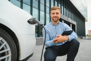 homme des charges un électrique voiture à le mise en charge station photo