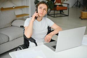 femme dans une fauteuil roulant travaux sur le portable PC dans le Accueil Bureau avec un assistance chien comme une un compagnon photo