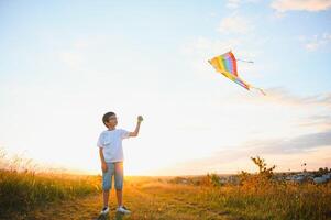 les enfants lancement une cerf-volant dans le champ à le coucher du soleil. photo