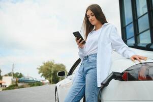 femme près de la voiture électrique. véhicule chargé à la borne de recharge. photo