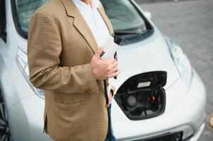 homme en portant Puissance connecteur pour électrique voiture photo