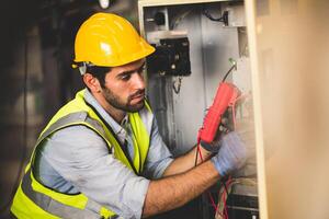 électrique ingénieur travail testeur mesure Tension et courant de Puissance électrique ligne dans électrique cabinet contrôle pour industriel production. photo