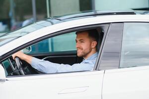 homme d'affaire en portant pilotage roue tandis que conduite moderne électrique voiture sur le rue route. sur de soi homme conduite coûteux auto. chauffeur tournant pilotage roue dans luxueux auto sur voyage photo