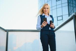 femme d'affaires avec téléphone près du bureau. portrait d'une belle femme souriante dans des vêtements de bureau de mode parlant au téléphone tout en se tenant à l'extérieur. communication téléphonique. image de haute qualité. photo