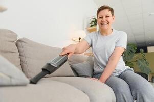 portrait de Sénior femme avec vide nettoyeur à l'intérieur à maison, aspirer photo