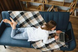 Jeune femme mensonge sur canapé avec portable. photo