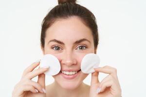 fermer portrait de Jeune femme la lessive sa affronter, prend de sa maquillage avec coton tampons, en utilisant faciale toner, soin de la peau nettoyant, permanent plus de blanc Contexte photo