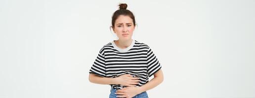 femme sentiment affamé, émouvant sa ventre. fille avec période crampes, menstruation douleur, détient mains sur estomac cette douleurs, isolé plus de blanc Contexte photo