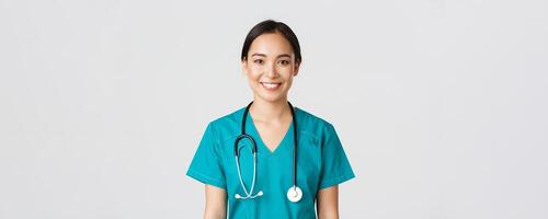 soins de santé ouvriers, empêcher virus, quarantaine campagne concept. fermer de souriant agréable asiatique femelle infirmière, médecin dans gommages à la recherche optimiste, écoute à patient, blanc Contexte photo