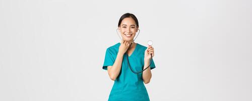 COVID-19 [feminine, soins de santé ouvriers et empêcher virus concept. de bonne humeur souriant asiatique femelle médecin, médecin consulter patient, examiner la personne avec stéthoscope, permanent blanc Contexte photo