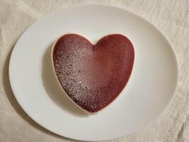 mousse gâteau dans une cœur forme sur une blanc plaque. le concept de la Saint-Valentin jour, de la mère jour, anniversaire, fête concept. photo