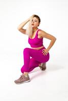 femme dans vibrant rose des sports tenue avec un le genou sur sol et autre courbé dans de face et main dans Cheveux photo