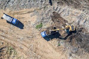 vue aérienne de dessus de l'excavatrice et des camions à benne basculante travaillant sur le chantier de construction photo