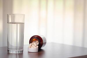 pilules et verre de l'eau sur en bois table dans le pièce photo